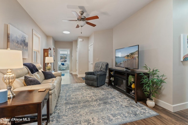 living room with wood finished floors, baseboards, and ceiling fan