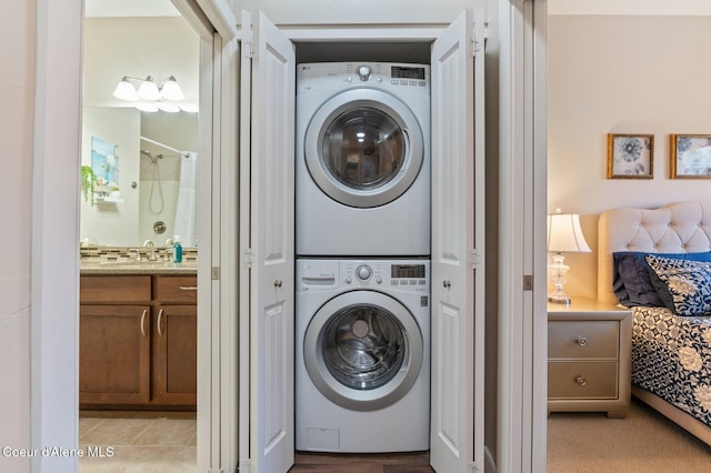 clothes washing area with laundry area, a sink, and stacked washer and dryer