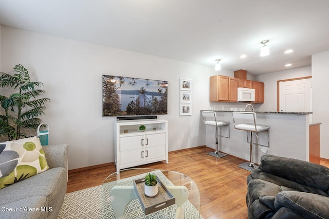 living room featuring recessed lighting, baseboards, and light wood-style floors