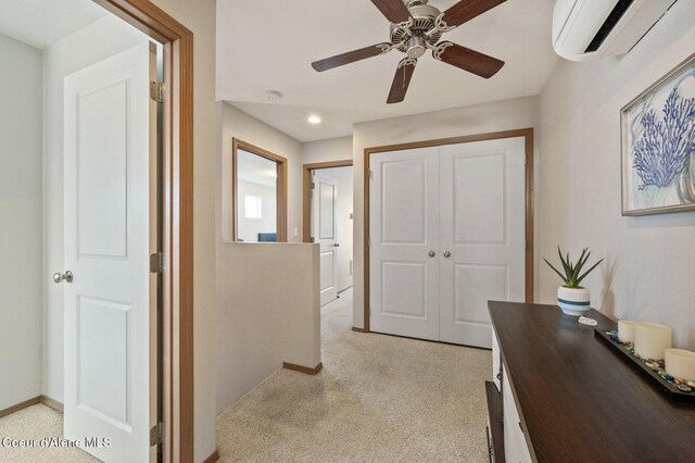 hall featuring an upstairs landing, light colored carpet, an AC wall unit, and baseboards