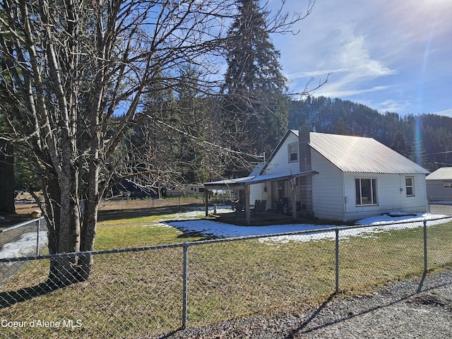 view of side of property featuring a yard, a fenced backyard, and metal roof