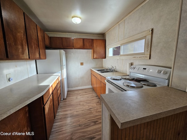 kitchen featuring light countertops, wood finished floors, a sink, and white appliances