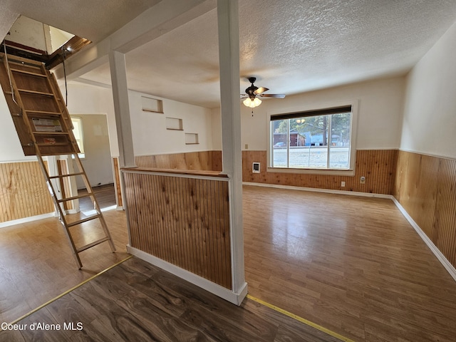 kitchen featuring a wainscoted wall, a textured ceiling, and wood walls