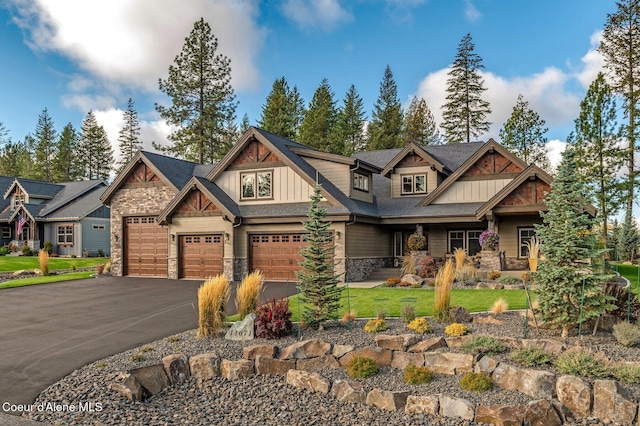 craftsman-style home featuring aphalt driveway, a garage, stone siding, board and batten siding, and a front yard