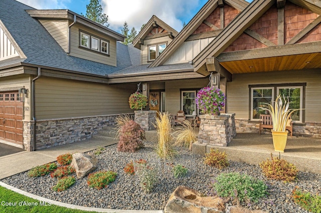 craftsman house with stone siding, covered porch, and roof with shingles