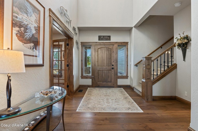 foyer entrance with stairs, visible vents, baseboards, and wood finished floors