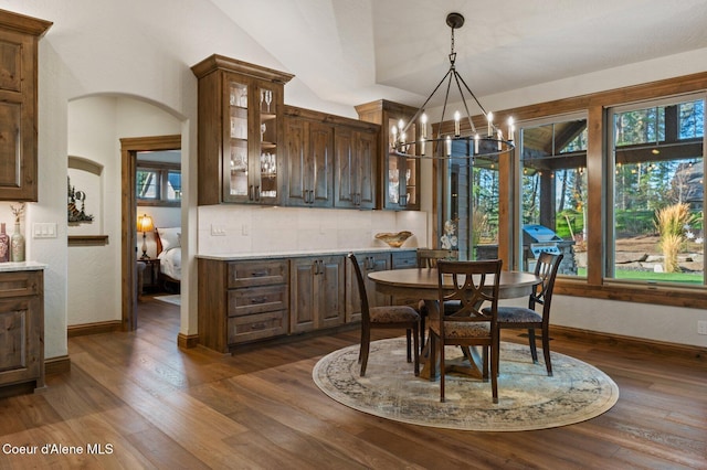 dining area featuring dark wood-style floors, a wealth of natural light, and arched walkways