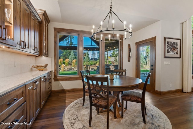 dining area featuring dark wood-style floors, a notable chandelier, and baseboards