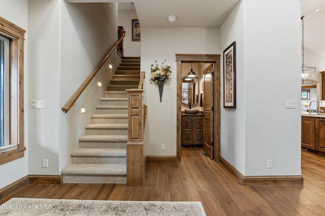 stairs with a chandelier, baseboards, and wood finished floors