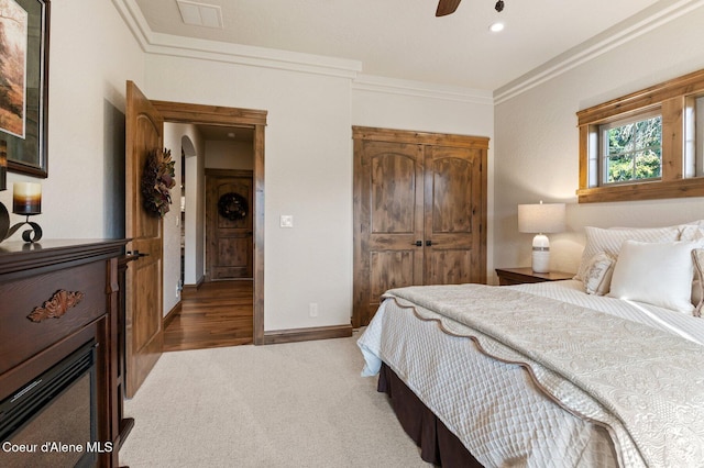 carpeted bedroom with arched walkways, a closet, baseboards, and crown molding