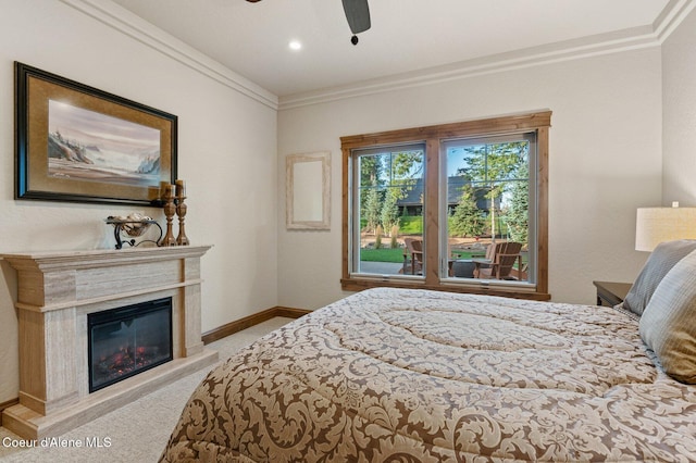 carpeted bedroom with ornamental molding, a glass covered fireplace, a ceiling fan, and baseboards