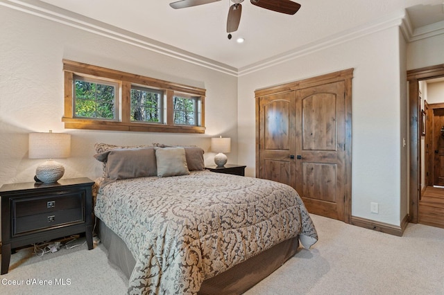 bedroom featuring baseboards, a ceiling fan, crown molding, carpet floors, and a closet