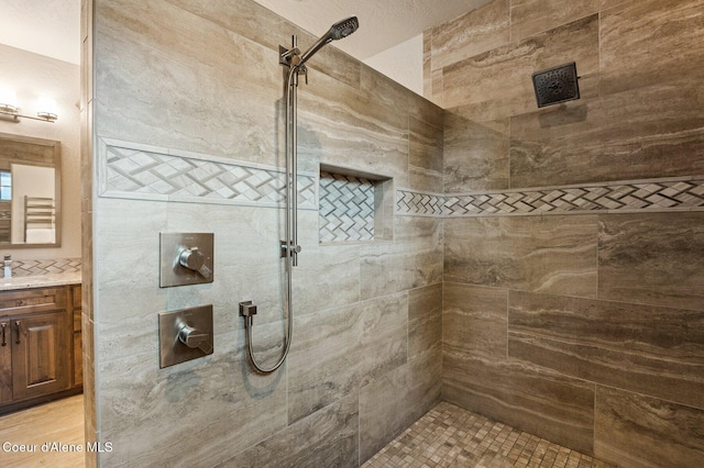 full bath with tiled shower and vanity