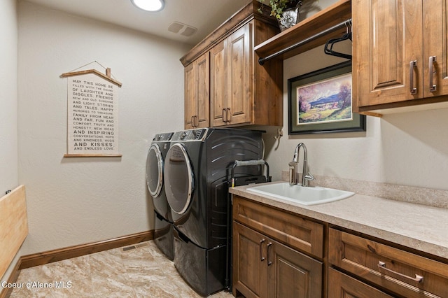 washroom featuring cabinet space, visible vents, baseboards, independent washer and dryer, and a sink