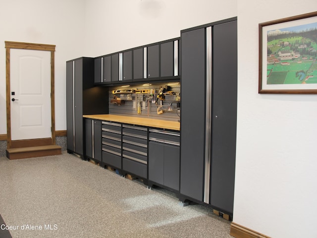 kitchen featuring gray cabinets, light carpet, butcher block counters, and baseboards