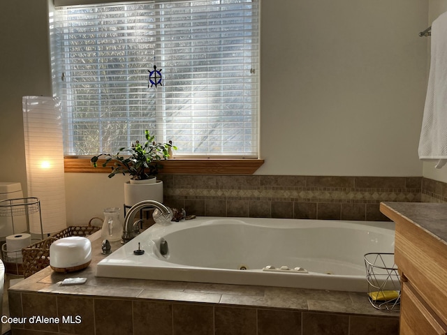 bathroom with a jetted tub, a wealth of natural light, and vanity