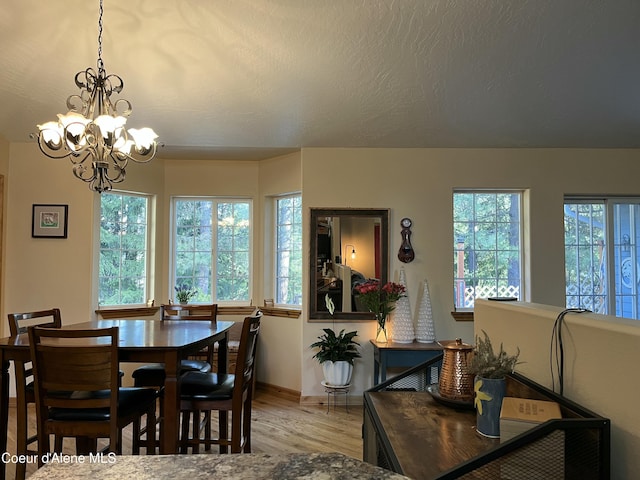 dining space featuring a chandelier, baseboards, a textured ceiling, and light wood finished floors