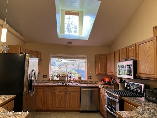 kitchen featuring a toaster, lofted ceiling, decorative light fixtures, stainless steel appliances, and a sink