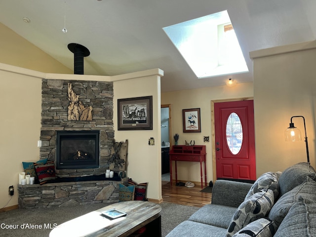 living area featuring vaulted ceiling with skylight, a fireplace, carpet flooring, and baseboards