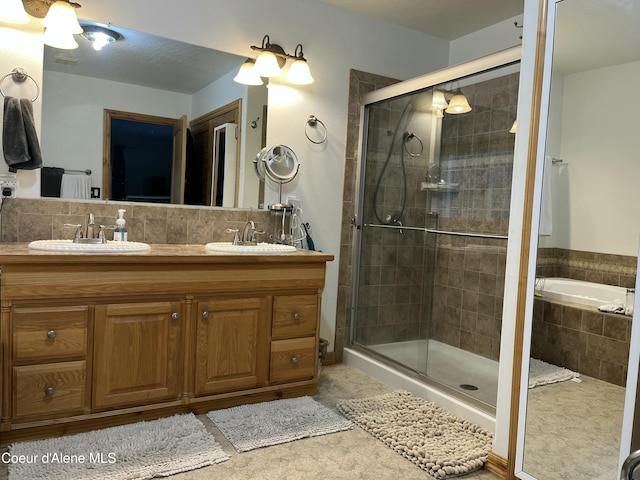 bathroom featuring double vanity, a shower stall, decorative backsplash, and a sink