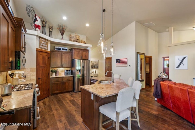 6489 E Kyong, Post Falls, ID 83854 - kitchen featuring a sink, stainless steel appliances, high vaulted ceiling, a breakfast bar area, and tasteful backsplash