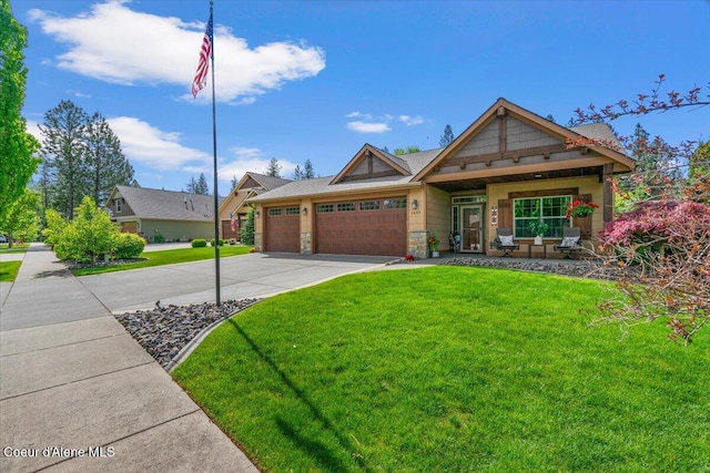6489 E Kyong, Post Falls, ID 83854 - view of front of house with a garage, concrete driveway, a front lawn, stone siding, and covered porch