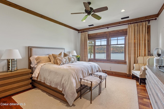 bedroom with a water view, crown molding, visible vents, and wood finished floors