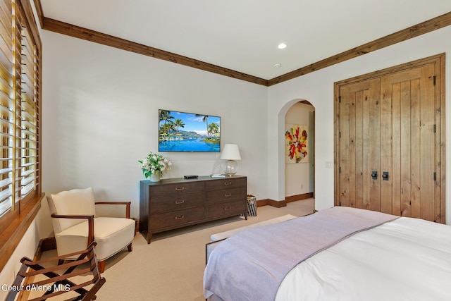 bedroom with arched walkways, carpet floors, baseboards, a closet, and crown molding