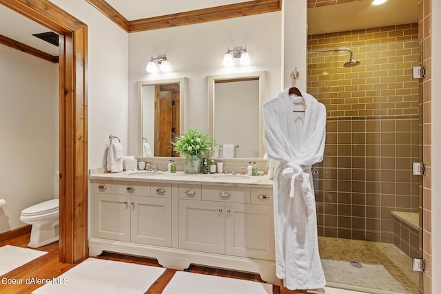 bathroom featuring ornamental molding, a stall shower, a sink, and wood finished floors