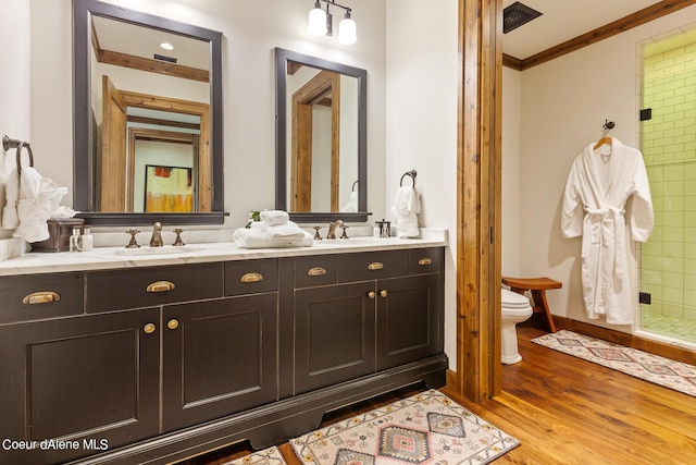 full bath with crown molding, double vanity, toilet, a sink, and wood finished floors