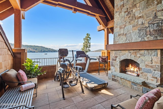 view of patio / terrace featuring an outdoor stone fireplace and a water view