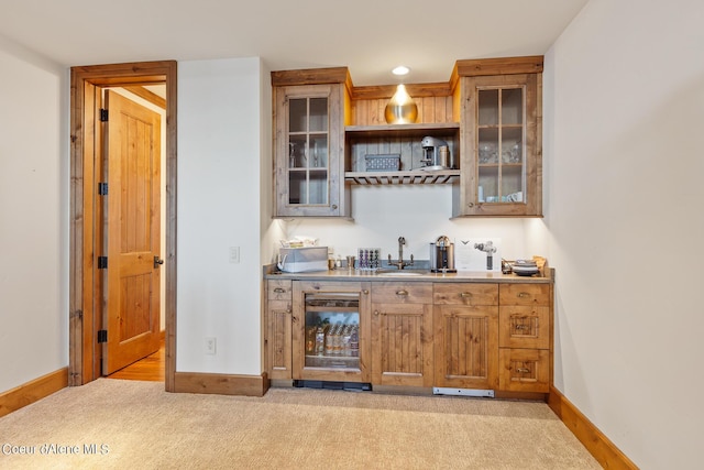 bar featuring light carpet, a sink, and baseboards