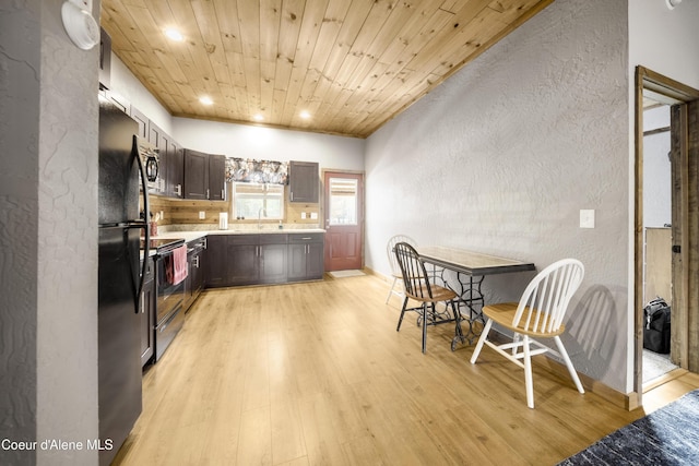 kitchen featuring light wood finished floors, stainless steel microwave, light countertops, wooden ceiling, and a textured wall