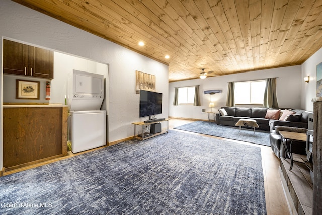 living room with wooden ceiling, stacked washer / drying machine, baseboards, ceiling fan, and a textured wall