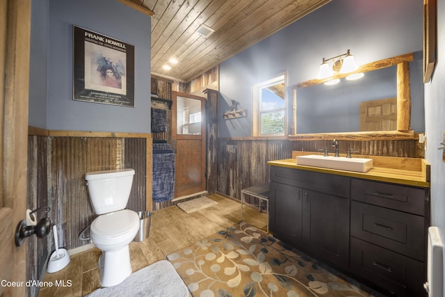 full bath with vanity, wood ceiling, wood walls, wainscoting, and toilet