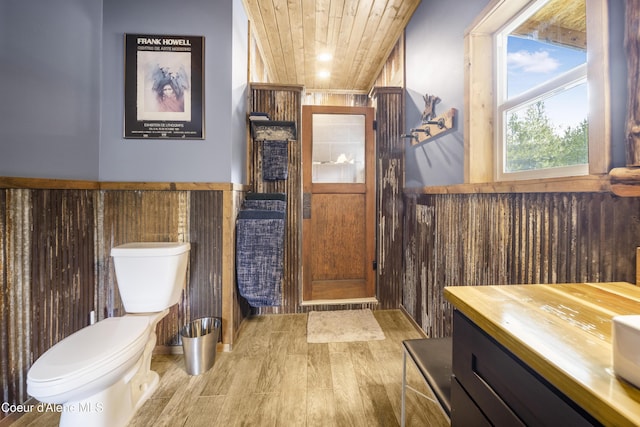 bathroom featuring wood ceiling, a wainscoted wall, toilet, and wood finished floors