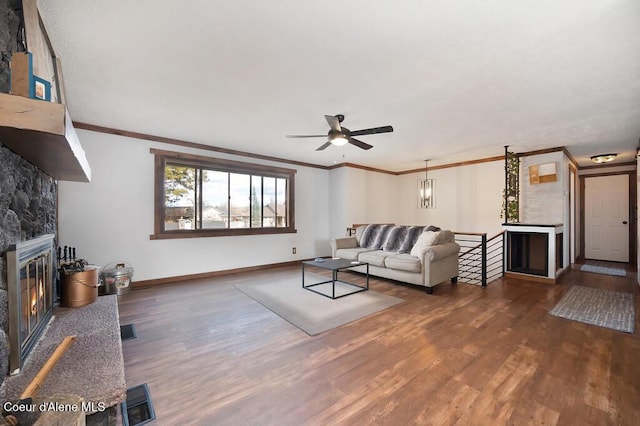 living room with ornamental molding, a fireplace, baseboards, and wood finished floors