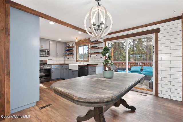 dining area with light wood finished floors, visible vents, and a chandelier