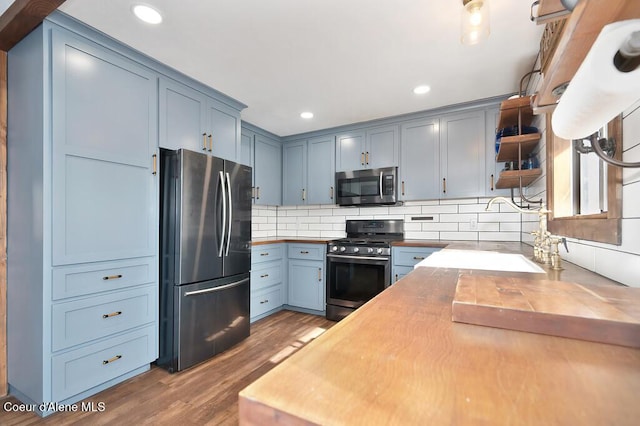 kitchen with butcher block countertops, open shelves, wood finished floors, appliances with stainless steel finishes, and decorative backsplash