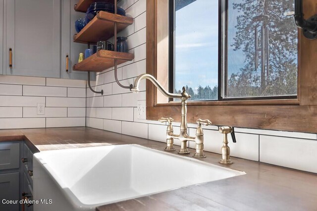 interior details featuring backsplash, gray cabinets, open shelves, and a sink