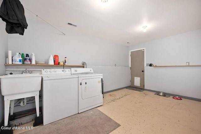 washroom with washing machine and clothes dryer, laundry area, baseboards, and a sink