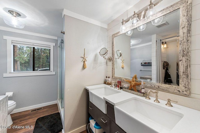 full bathroom with wood finished floors, visible vents, a sink, a shower stall, and toilet