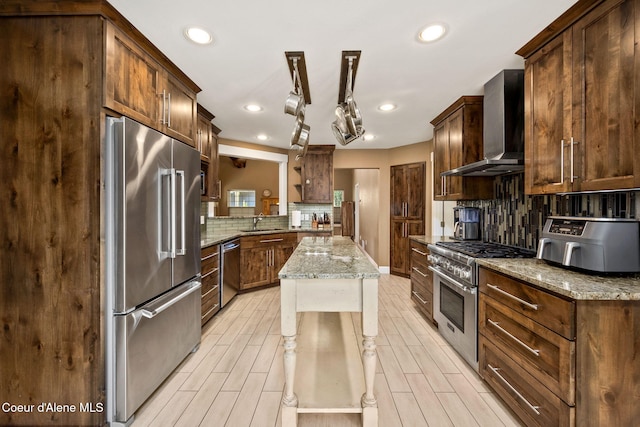 kitchen featuring a sink, wall chimney exhaust hood, tasteful backsplash, and premium appliances