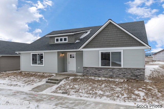 view of front of house featuring stone siding and a shingled roof