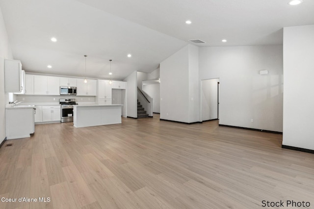 kitchen featuring light wood-style flooring, stainless steel appliances, a sink, visible vents, and light countertops