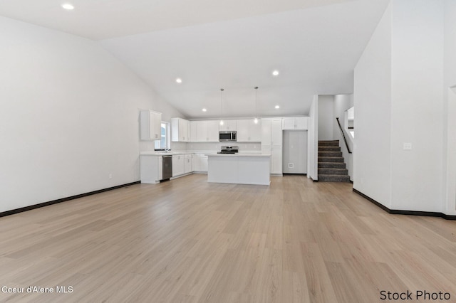 unfurnished living room with stairs, light wood-type flooring, lofted ceiling, and baseboards