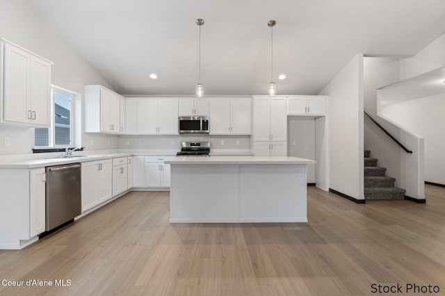 kitchen featuring light wood finished floors, lofted ceiling, appliances with stainless steel finishes, light countertops, and white cabinetry