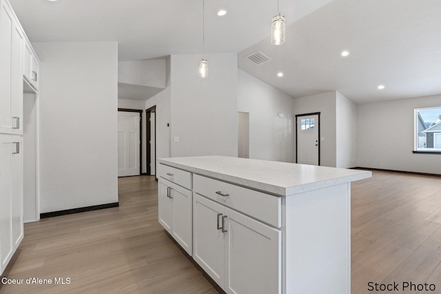 kitchen with light countertops, a kitchen island, visible vents, and light wood-style floors