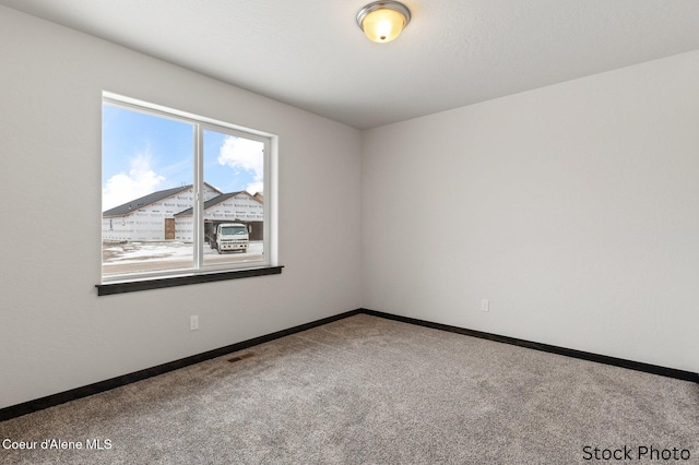 empty room with carpet floors, visible vents, and baseboards