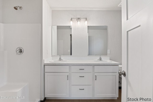 full bathroom featuring double vanity, walk in shower, and a sink